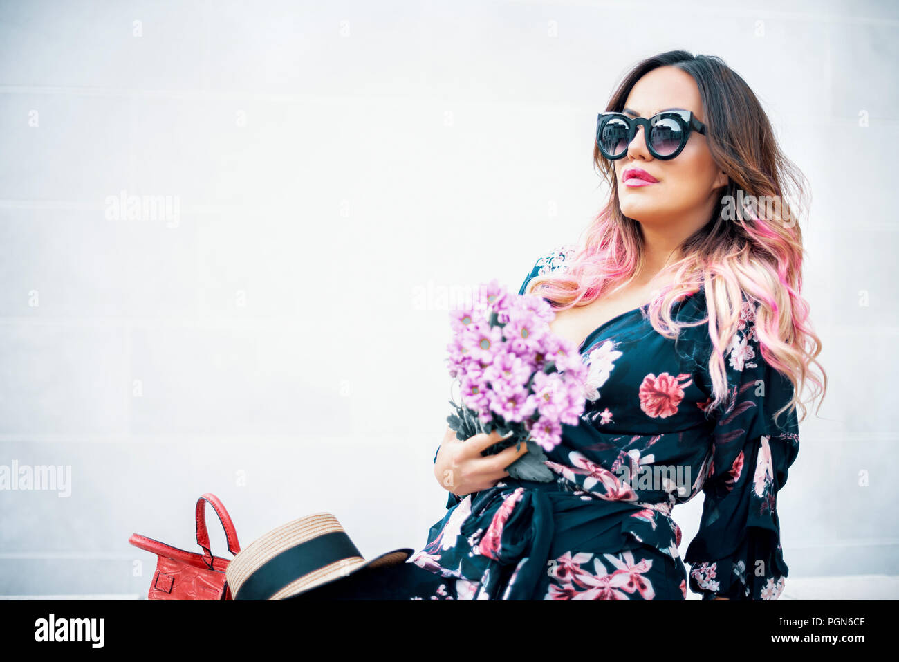 Belle femme sensuelle fashion avec fleurs et hat posing sur mur de pierre blanche. La tonalité de l'image. Banque D'Images