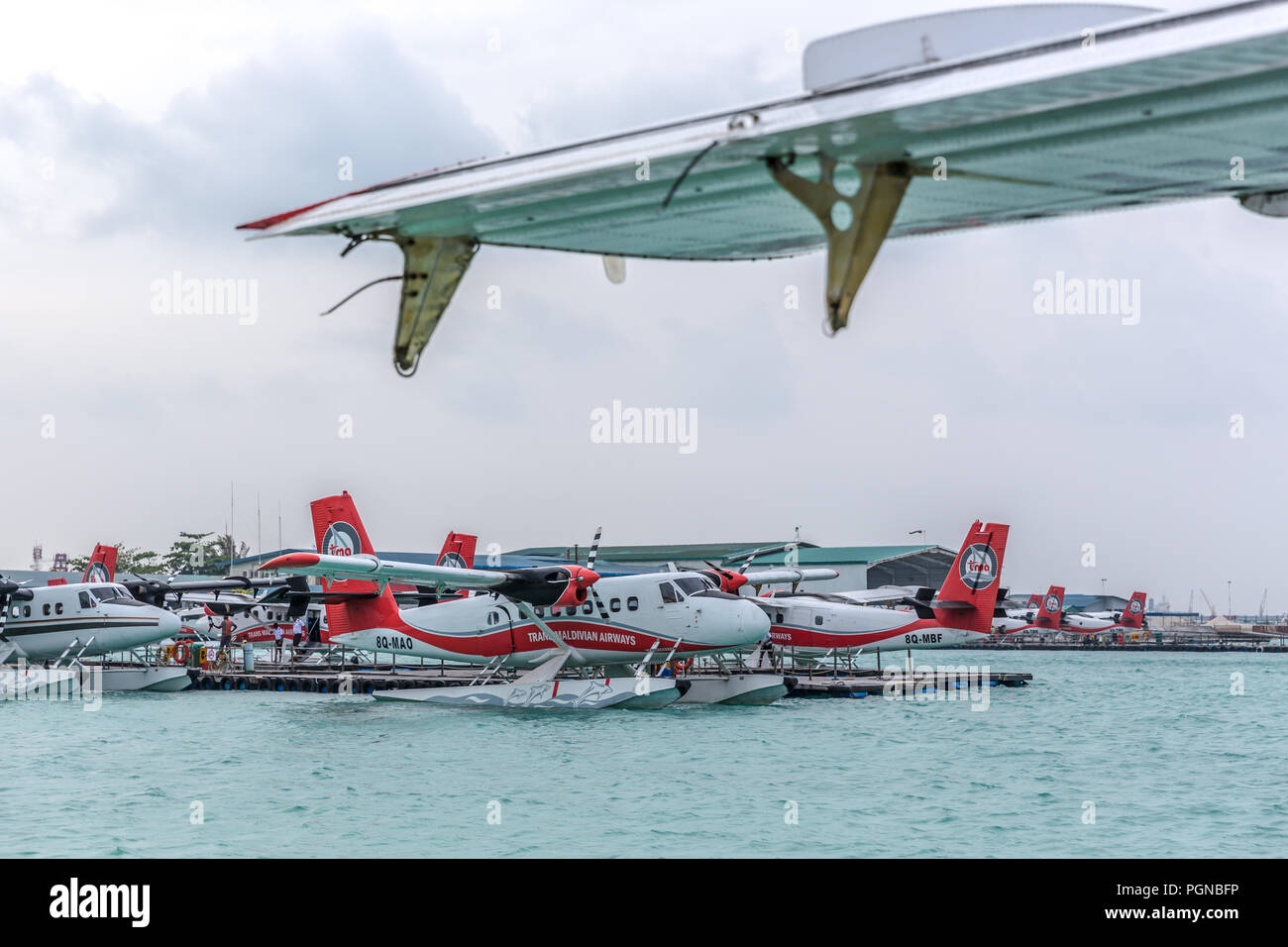 Les Maldives, 10 février 2018 - Un hydravion flottant dans l'eau bleu des Maldives, à proximité d'un pont en bois avec quelques nuages dans le ciel. Banque D'Images