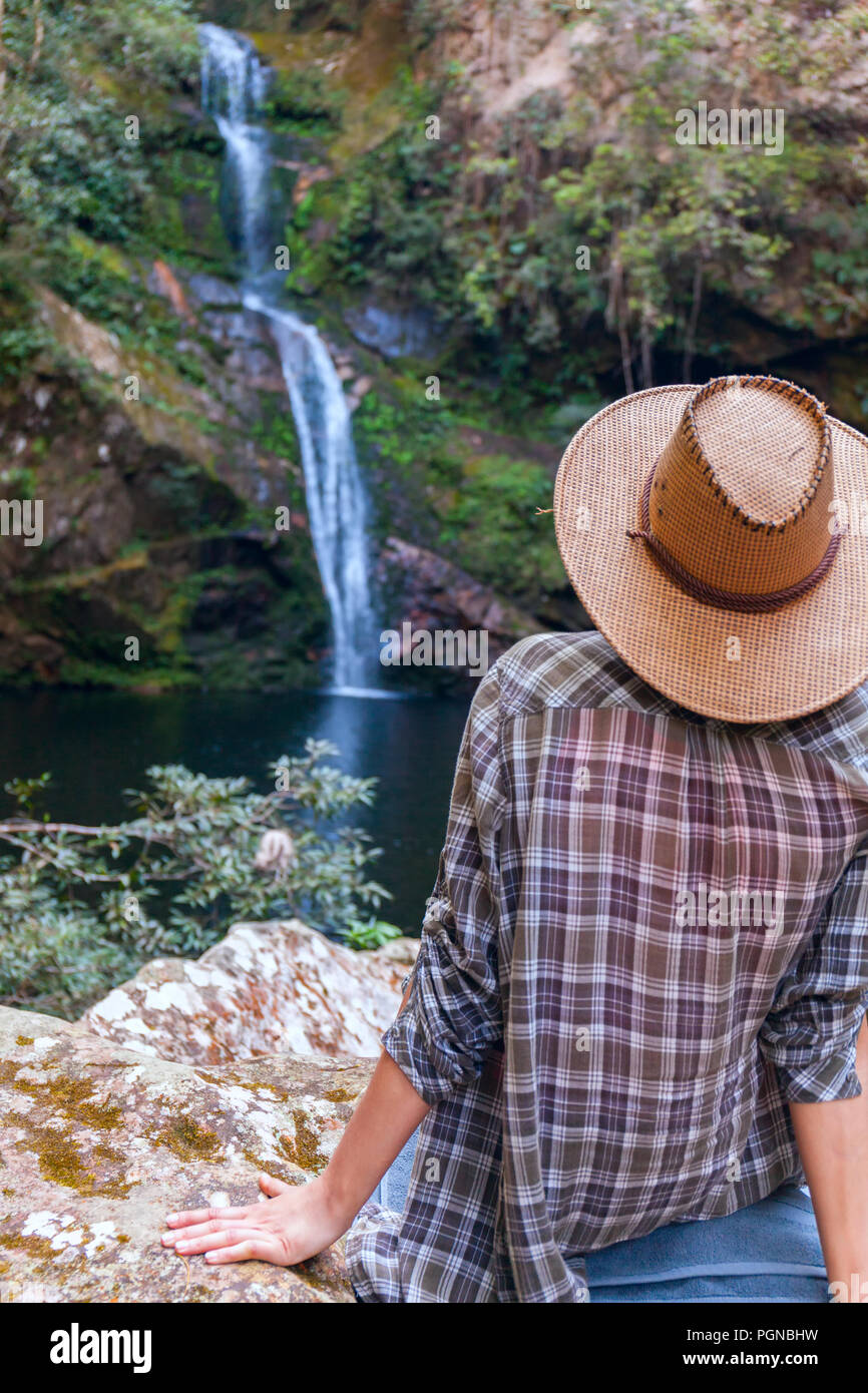 Vue arrière de jeune fille en chapeau de paille et à la recherche à cascade. Jeune femme de race blanche se penche sur la chute de l'eau, photo sur l'air frais. jeunes adolesce dans la nature sauvage Banque D'Images