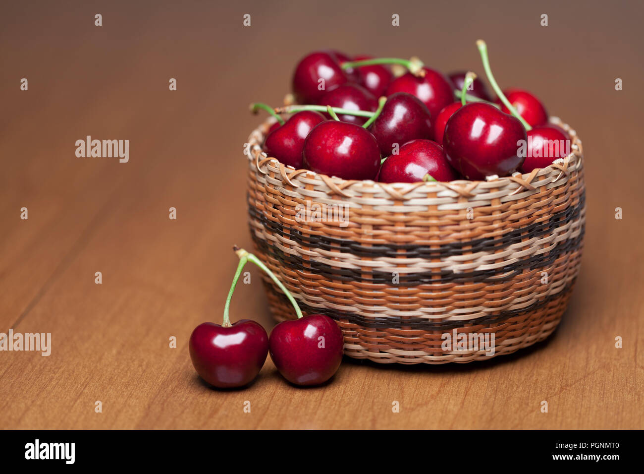 Les cerises mûres rouges dans un panier sur une table en bois Banque D'Images