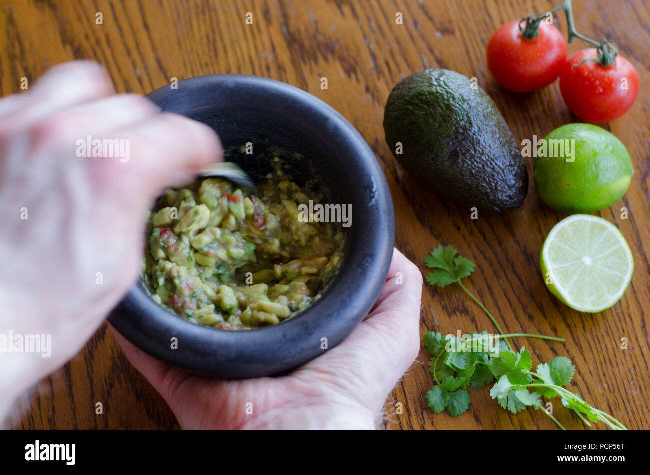 Faire le guacamole dans un mortier avec les ingrédients montrant sur l'arrière-plan Banque D'Images Faire le guacamole dans un mortier avec les ingrédients montrant sur l'arrière-plan Banque D'Images