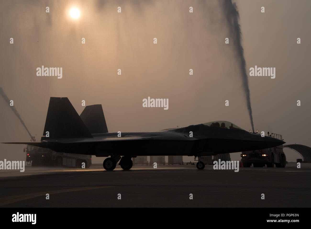 Le général Jeffrey L., Harrigian US Air Forces Central Command, est pulvérisé avec de l'eau cérémonieusement les camions d'incendie, après avoir effectué son dernier vol, vol, ou "fini" dans un F-22 Raptor à Al Dhafra Air Base, 8 août 2018. Comme le commandant de la composante aérienne des Forces combinées, l'américain mène, le joint, et opérations coalisées dans la zone de responsabilité, une zone couvrant 20 pays de l'Égypte à l'Afghanistan. (U.S. Air Force photo de Tech. Le Sgt. Nieko Carzis) Banque D'Images