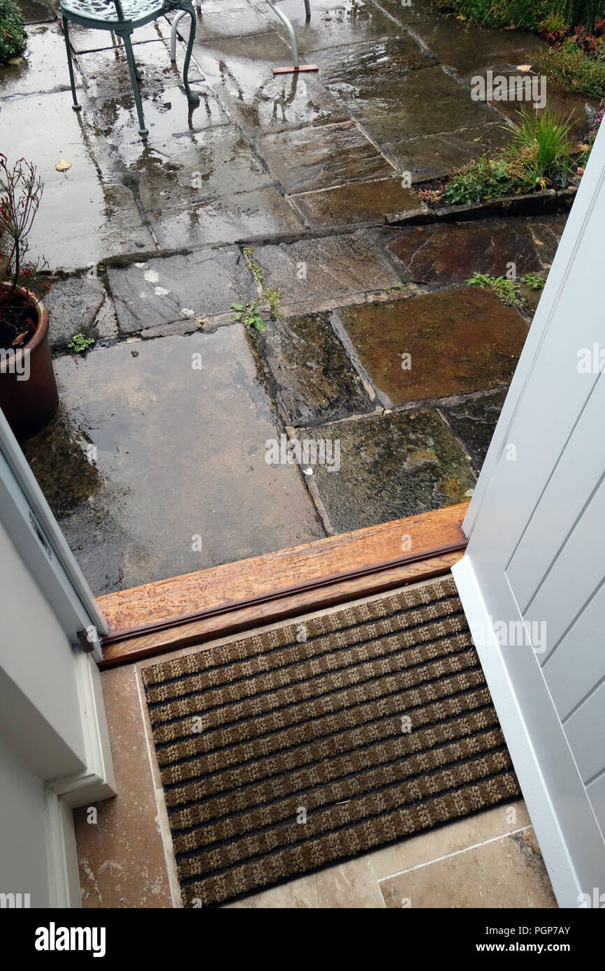 Ouvrez la porte d'un chalet de la porte pour voir la pluie sur les dalles de patio en pierre à Sheffield, Yorkshire, Angleterre. Banque D'Images