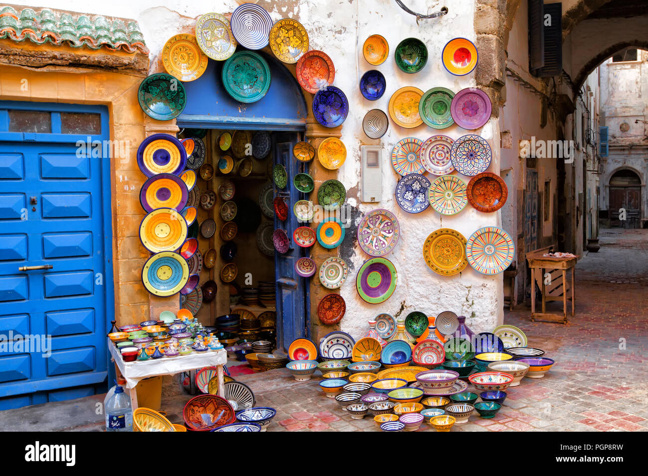 Maroc poterie colorée sur l'écran en vente dans une ruelle pittoresque. Des plaques de couleurs ornent les murs à l'extérieur d'un magasin. Lieu : Essaouira Banque D'Images