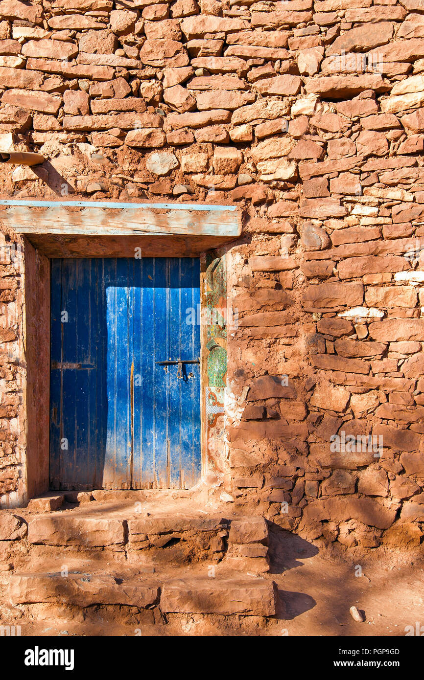 Maroc vieux mur de pierre avec une porte peinte en bleu. Deux marches de pierre mènent à la porte. Banque D'Images