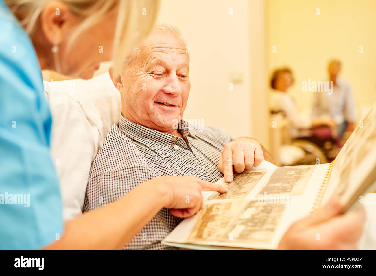 Senior man with dementia regarde photos ensemble avec la pression dans la maison de soins infirmiers Banque D'Images
