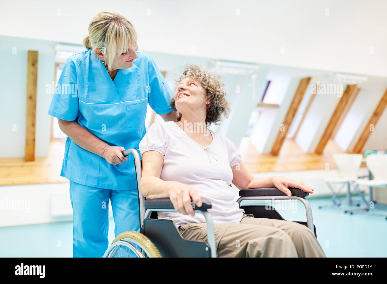 Le fournisseur de soins prend soin d'un senior femme dans un fauteuil roulant à rehab Banque D'Images