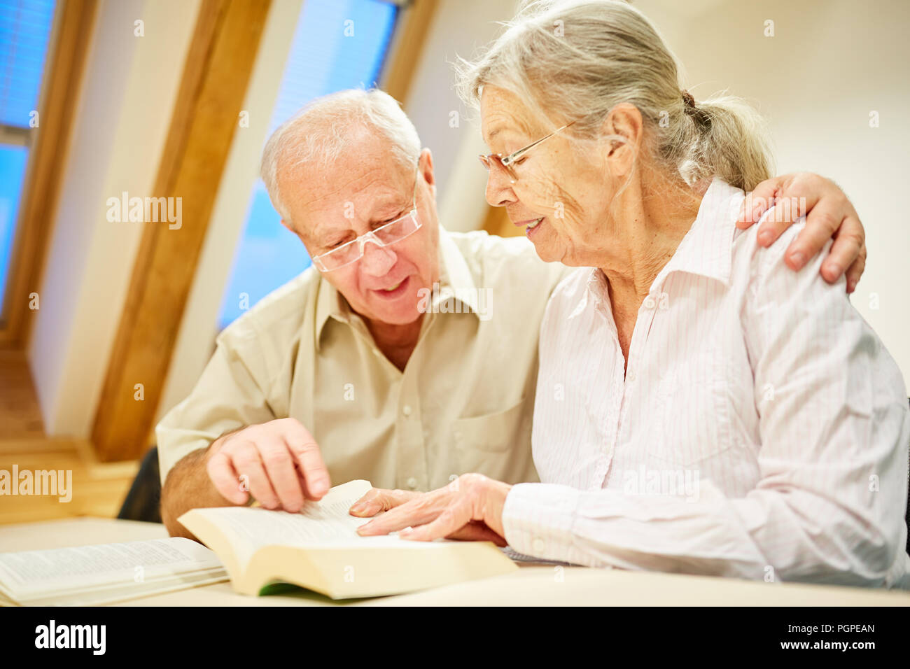 Couple de lecture de livres et de la lecture à haute voix dans une maison de soins infirmiers ou à la maison Banque D'Images