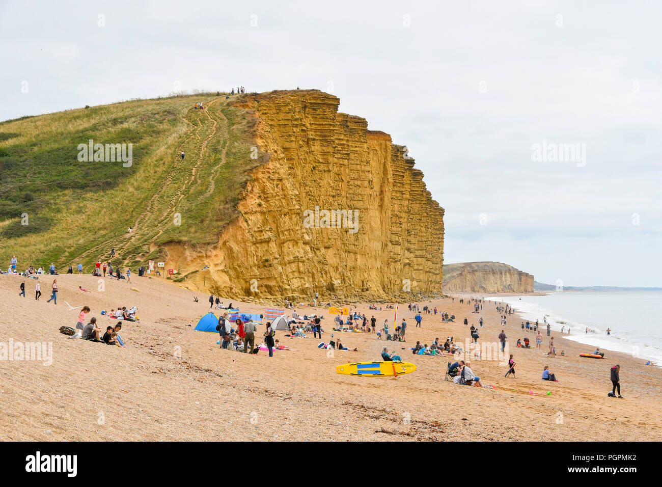 West Bay, Dorset, UK. 28 août 2018. Météo britannique. Les vacanciers sur la plage à la station balnéaire de West Bay dans le Dorset bénéficiant d'un accueil chaleureux, mais surtout jour nuageux. Crédit photo : Graham Hunt/Alamy Live News Banque D'Images