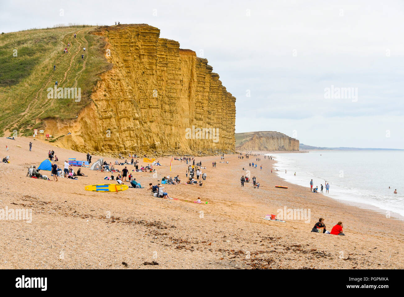 West Bay, Dorset, UK. 28 août 2018. Météo britannique. Les vacanciers sur la plage à la station balnéaire de West Bay dans le Dorset bénéficiant d'un accueil chaleureux, mais surtout jour nuageux. Crédit photo : Graham Hunt/Alamy Live News Banque D'Images