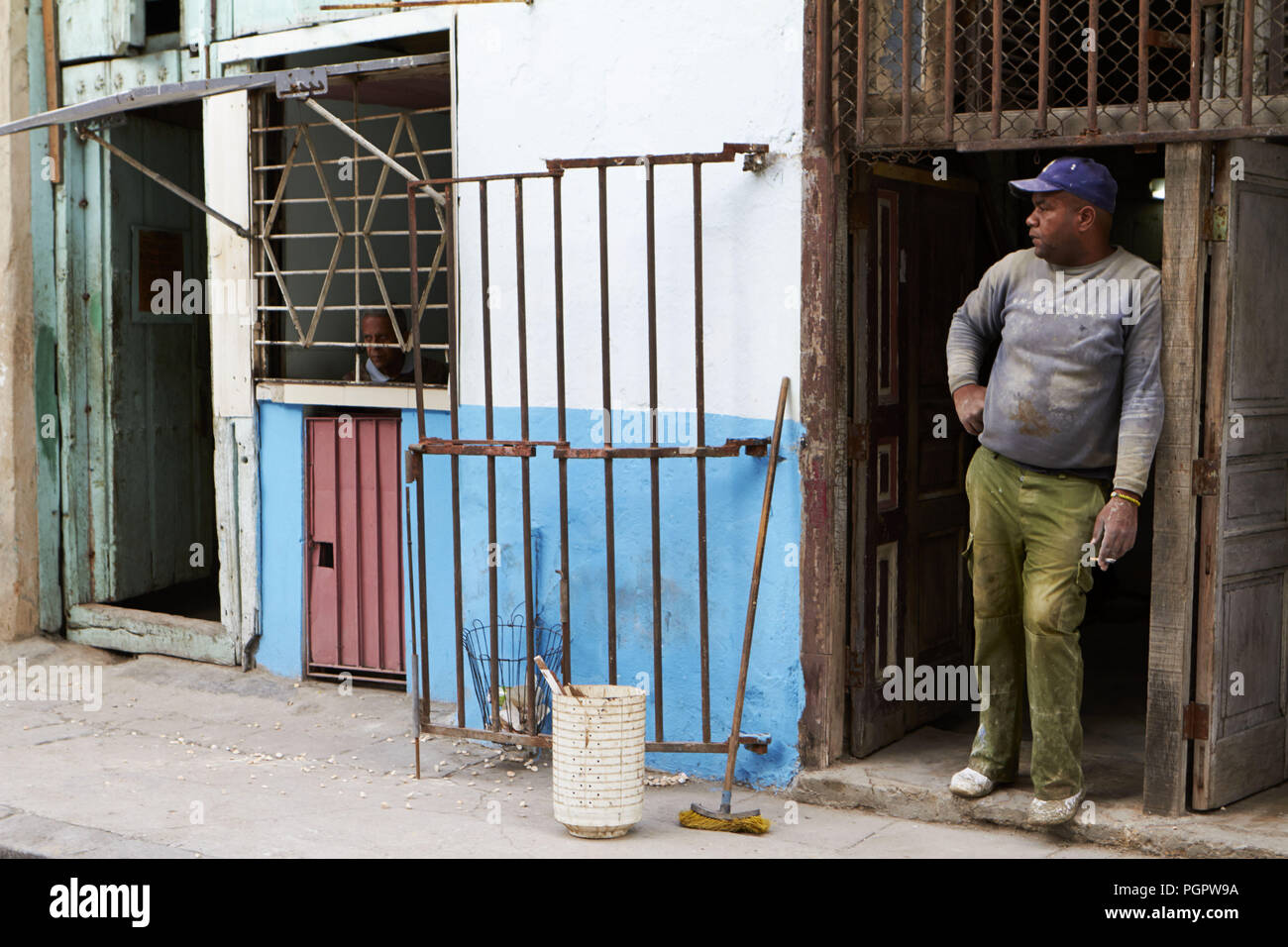 La Havane, Cuba. 17 Jan, 2014. Un travailleur de la construction prend une pause et fume une cigarette comme l'homme qui vit à côté de pairs hors de sa fenêtre à La Havane. Peu de choses ont changé pour la classe moyenne de Cuba. Ils vivent toujours dans un cas isolé, les limiter, la société communiste. Si un petit nombre de nouvelles installations modernes telles que la connexion Wi-Fi au réseau local ont fait leur chemin à Cuba la plupart des Cubains ne peuvent pas se permettre de l'utiliser régulièrement. Credit : Allison Dîner/ZUMA/Alamy Fil Live News Banque D'Images