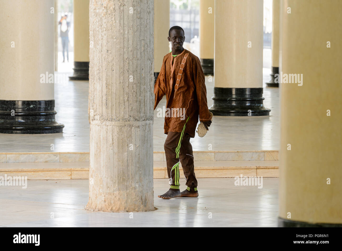 TOUBA, SÉNÉGAL - 26 avr 2017 : sénégalais non identifiés homme marche derrière la colonne de la Grande Mosquée de Touba, l'accueil de la confrérie Mouride Banque D'Images