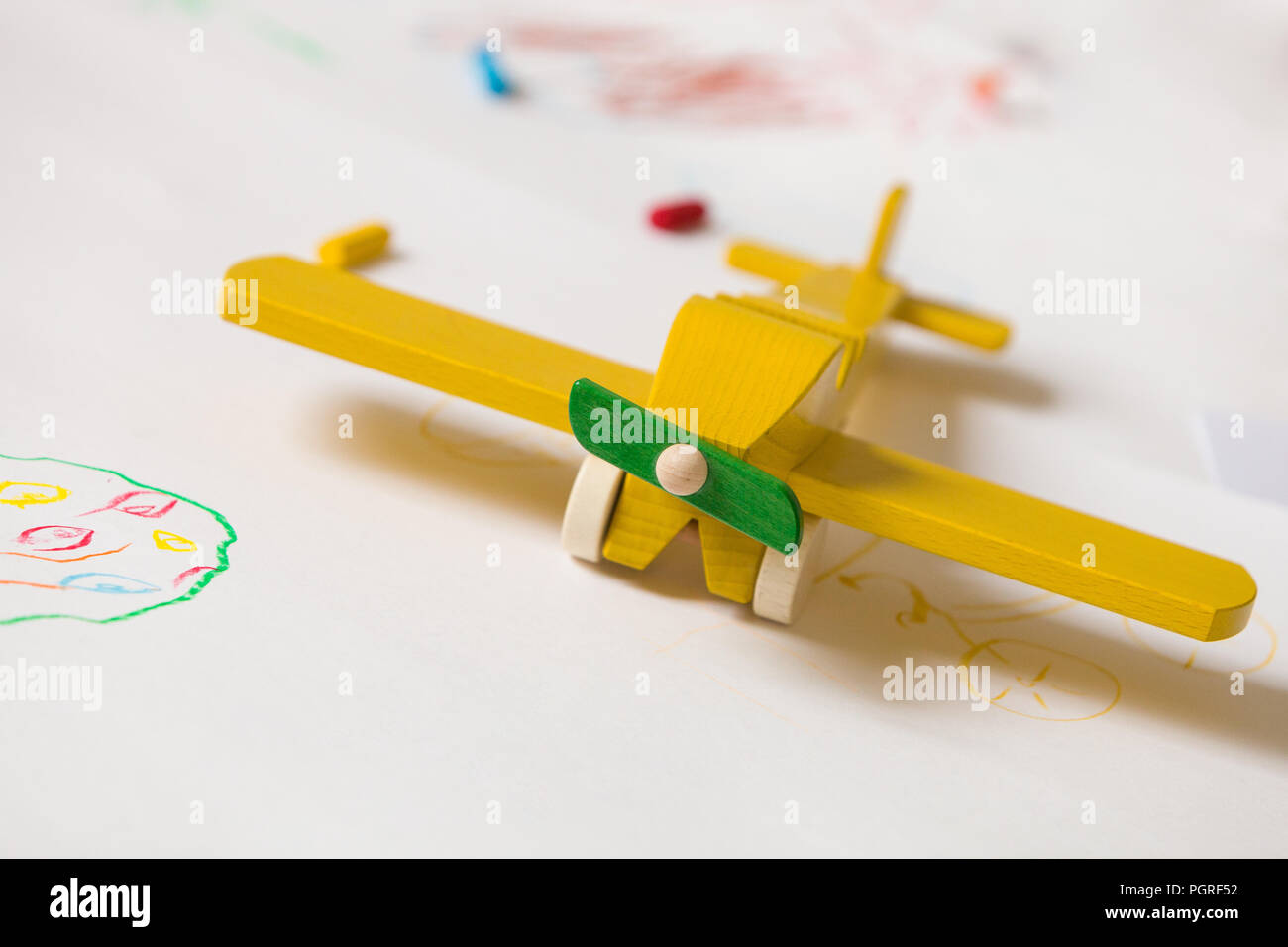 Avion jouet en bois jaune sur le fond blanc. L'éducation, les enfants, jouer concept. Dessins pour les enfants avec le jouet. L'enfance. Heureux. La joie. Le jardin d'enfants. Banque D'Images