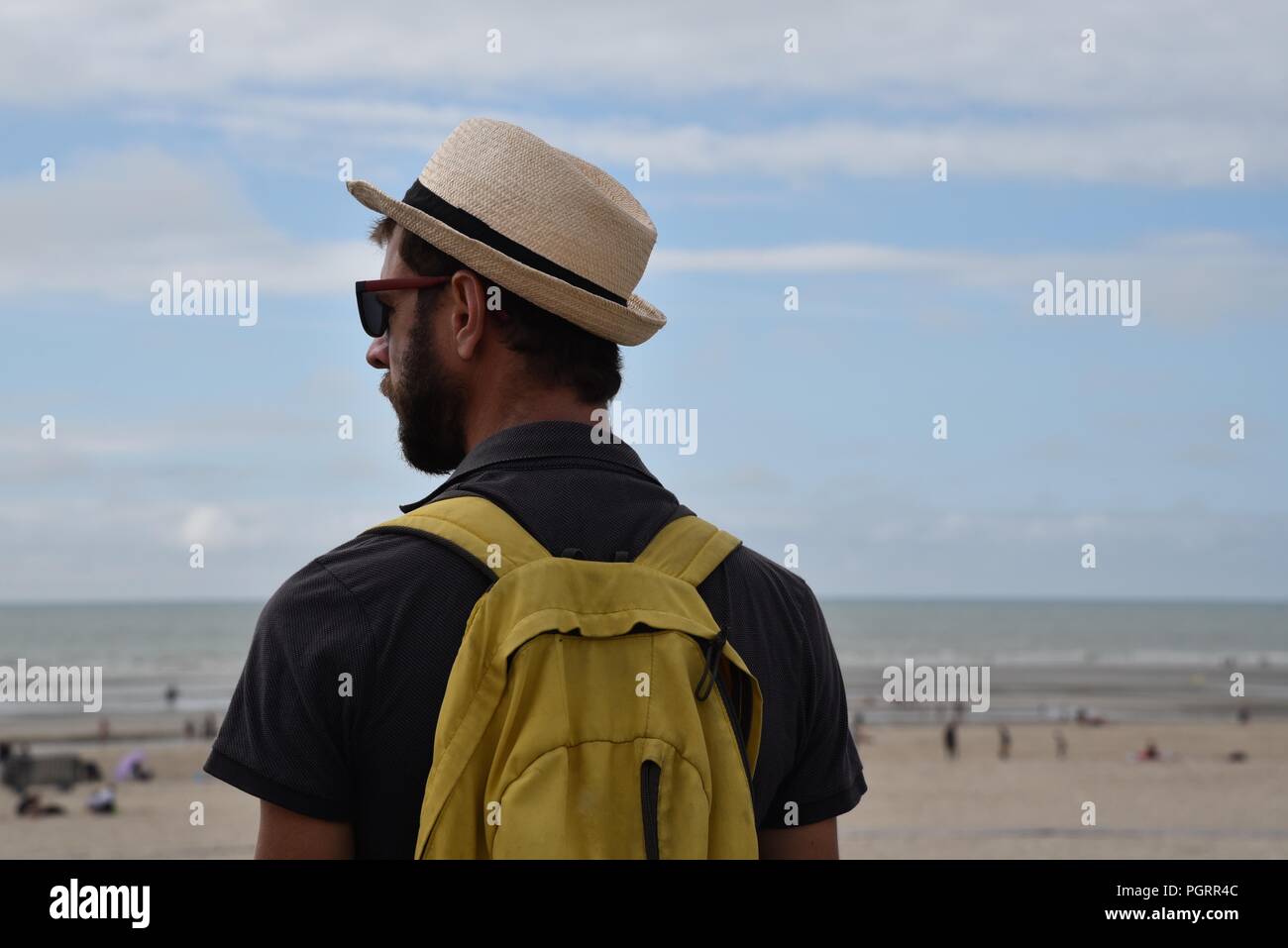 Jeune homme : un homme seul, barbu portant un chapeau de paille et un sac à  dos souple donne sur la plage de paris-plage du Touquet dans le nord de la  France