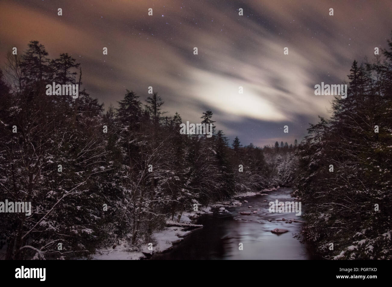 Strie de nuages de l'ensemble de l'Ouest Virginien ciel nocturne passant sur la rivière Blackwater et les pins couverts de neige ci-dessous dans cette longue exposition. Banque D'Images