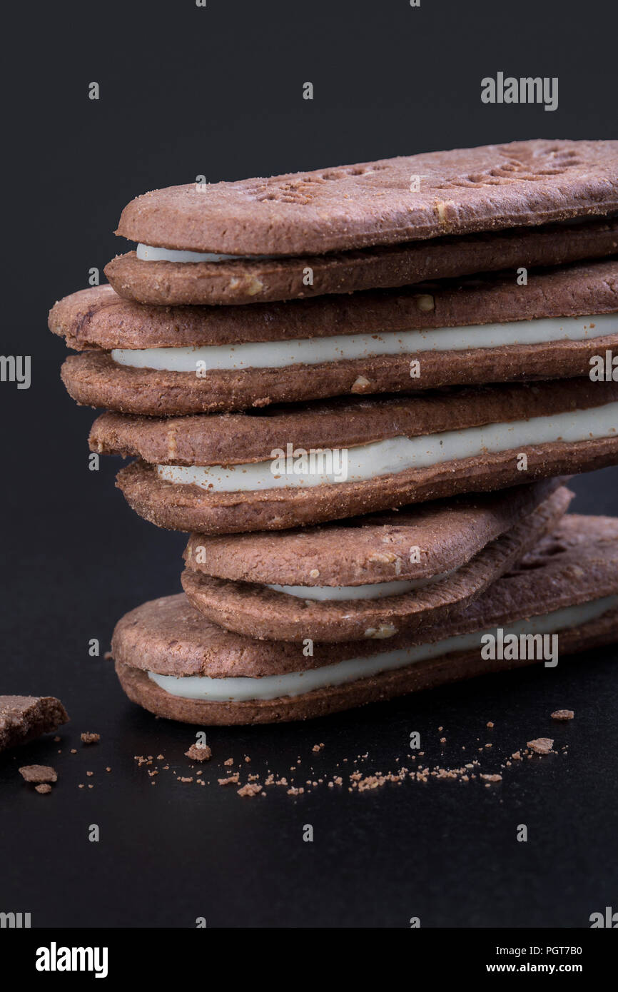 Sandwich cookies au chocolat avec crème blanche sur fond noir, close-up side view Banque D'Images