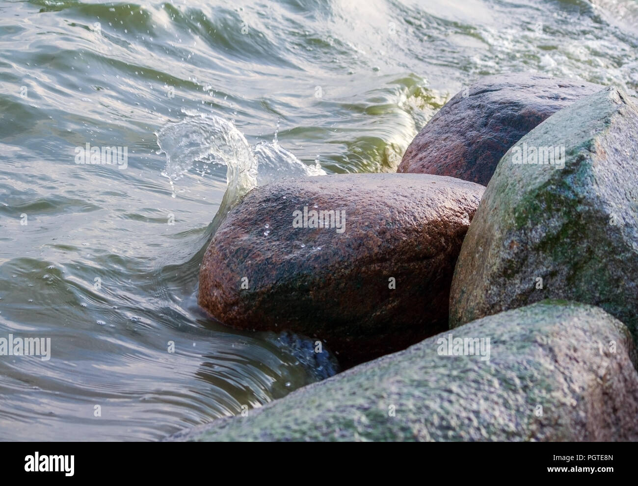 Quatre grosses pierres de granit situé près de l'eau, l'eau sous la forme d'une vague distincte est brisée contre les pierres, un léger coup de feu, l'eau Banque D'Images