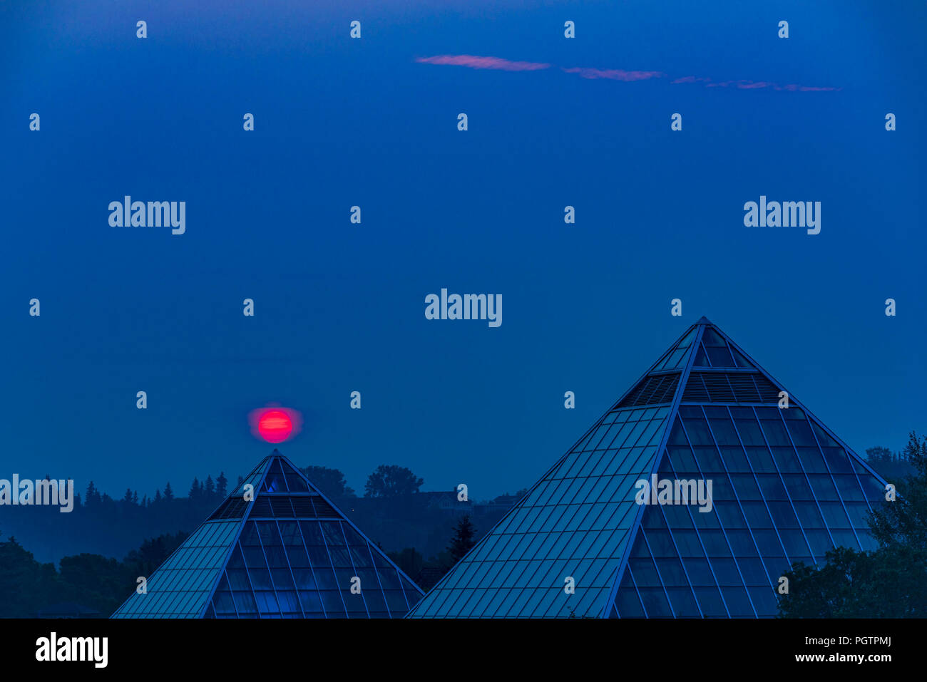 Soleil se lève à travers la fumée rempli ciel, Muttart Conservatory Pyramids, Edmonton, Alberta, Canada. Banque D'Images