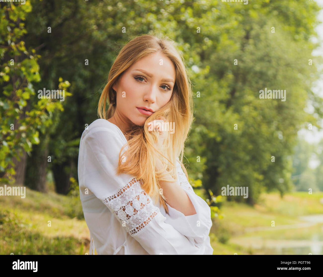 Jolie jeune femme en robe blanche sur le lac en plein air dans la nature, méditer Banque D'Images