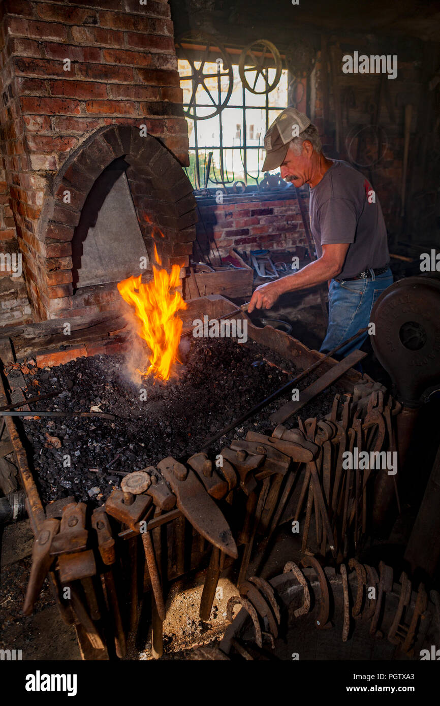 Un forgeron ajuste l'incendie de sa fournaise dans l'atelier de reproduction à Peacham, Vermont, United States. Banque D'Images