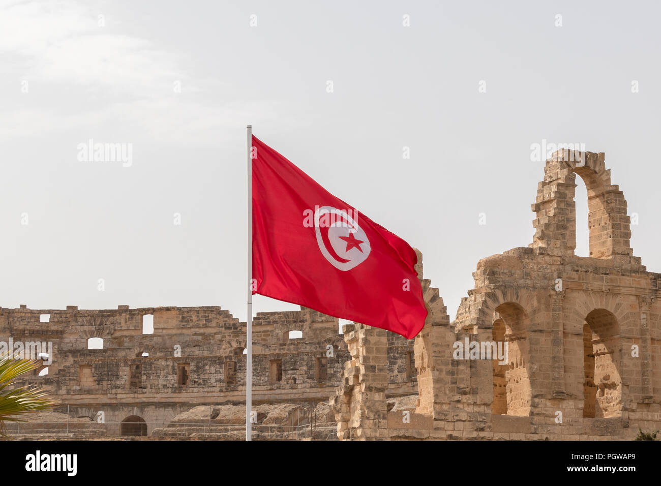 Le drapeau rouge et blanc de la Tunisie, sur l'arrière-plan sont les ruines de l'Amphithéâtre Romain d'El Jem, Tunisie, Afrique Banque D'Images