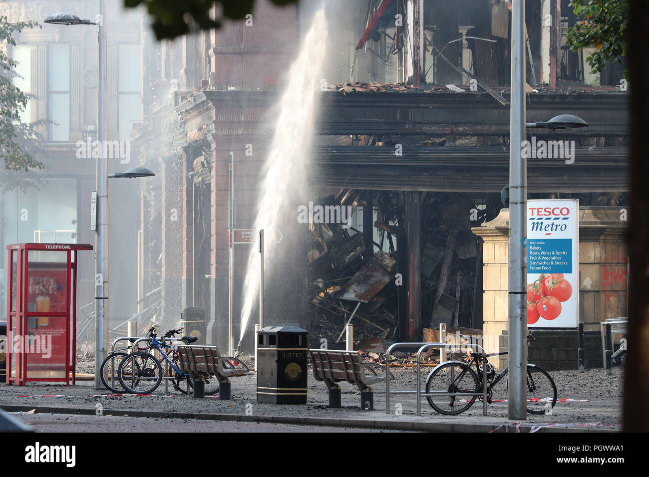 Les lances à incendie pulvériser de l'eau pour refroidir l'intérieur de la combustion des braises Primark store dans le centre-ville de Belfast, où un important incendie a éclaté mardi. Banque D'Images