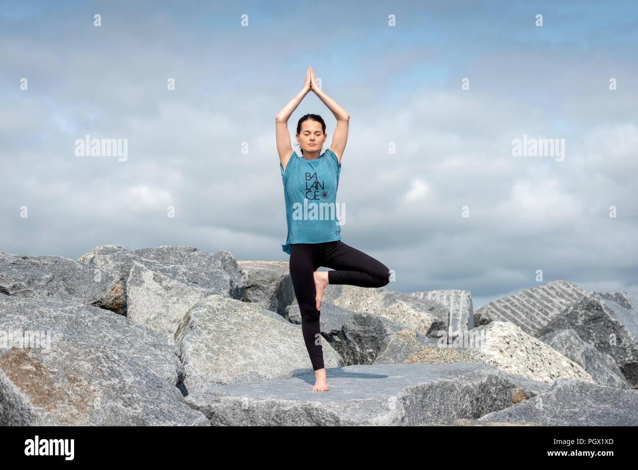 Woman doing yoga, posture de l'arbre, portant un tshirt "d'équilibre" slogan. Banque D'Images