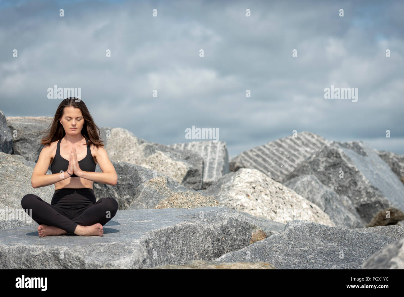 Femme assise méditant à l'extérieur sur les roches, copyspace. Banque D'Images