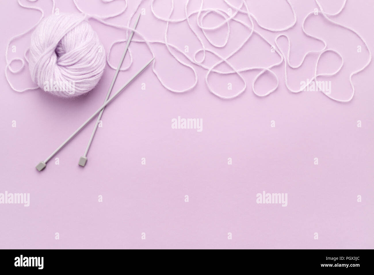 Fil lilas pelote, aiguilles à tricoter et à la frontière de thread sur lilac copie espace. Vue de dessus, la couture concept. Banque D'Images