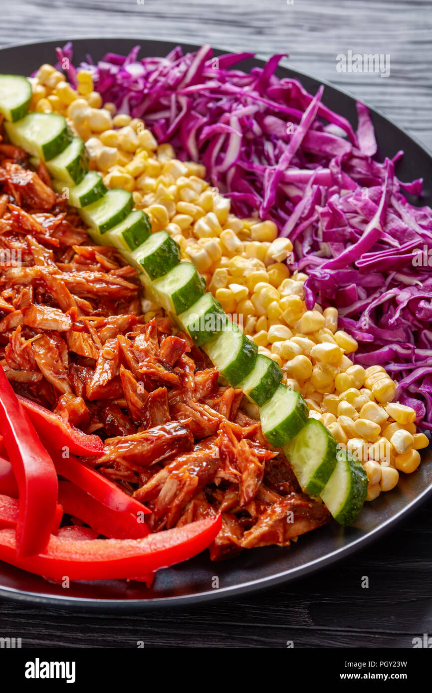 Porc à la mijoteuse avec salade rancho organisé rangées de fines tranches de chou rouge, maïs, poivron, concombre et jalapeno haché noire sur une pla Banque D'Images