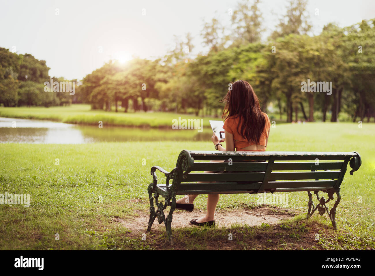 Vue arrière de l'heureux beauty woman en tenues décontractées à l'aide de tablette en arrière-plan de parc national. Les modes de vie des gens et de la technologie du concept. La nature et relax Banque D'Images