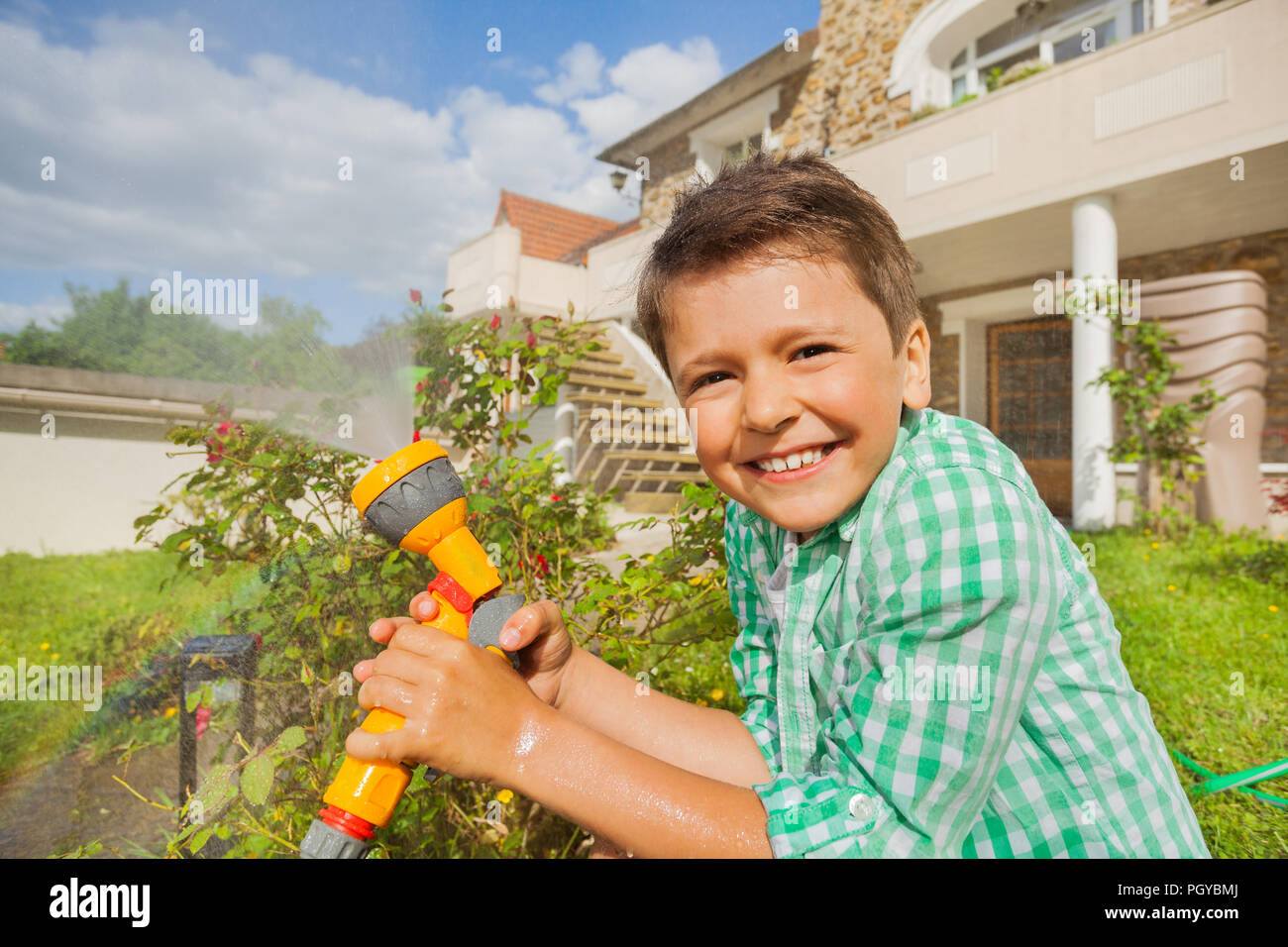 Close-up portrait of happy boy d'arrosage jardin avec arrosage à main en été Banque D'Images