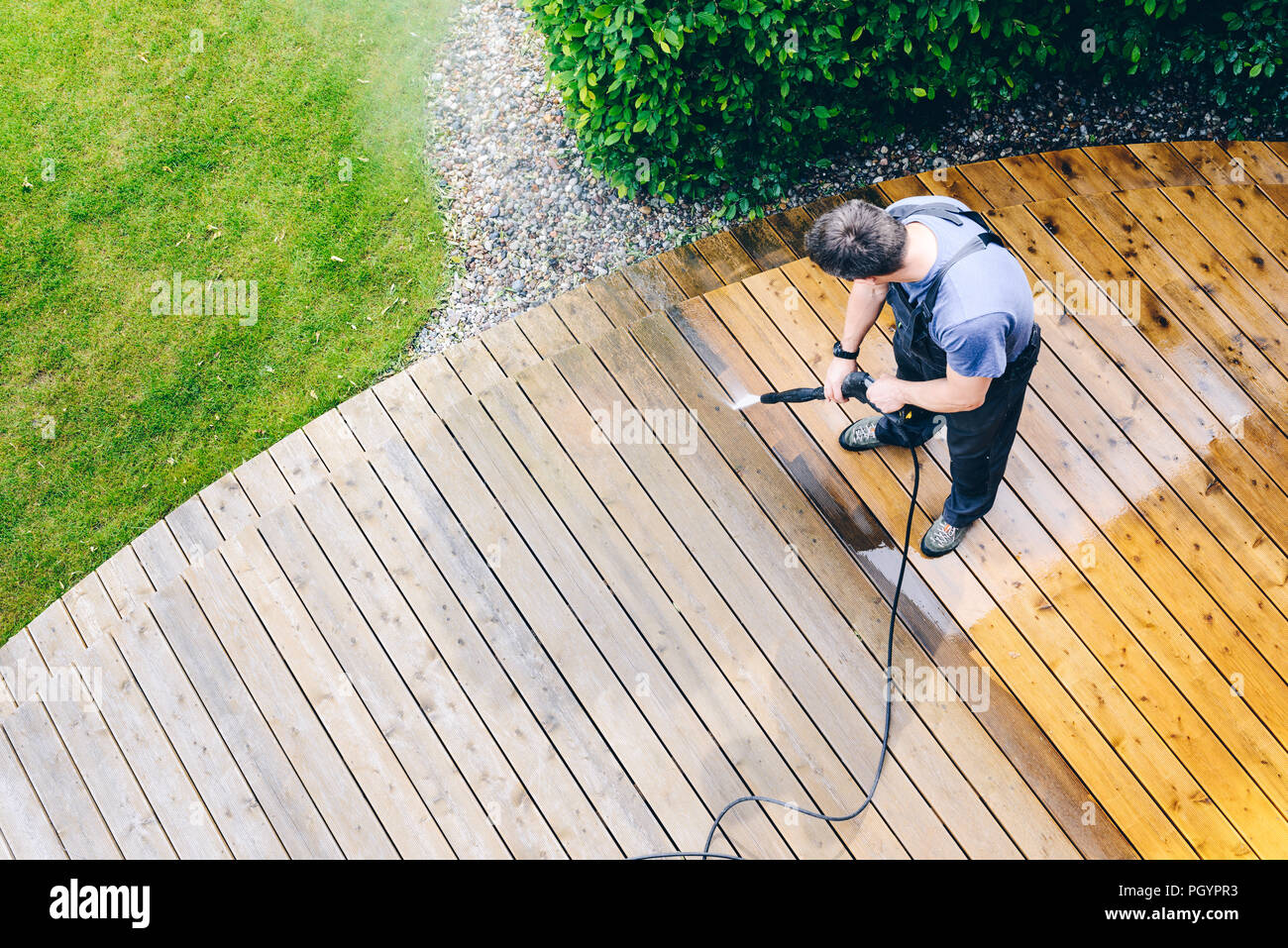 Nettoyage homme terrasse avec une laveuse à haute pression de l'eau -  produit nettoyant sur la surface de terrasse en bois Photo Stock - Alamy