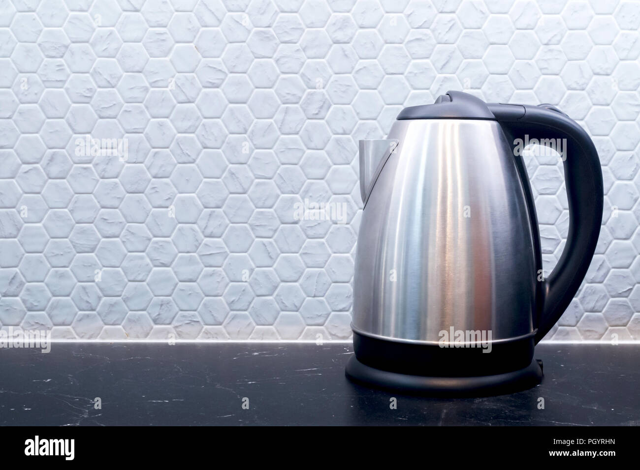 Bouilloire électrique en acier inoxydable ustensiles sur un comptoir en marbre noir marquina dans la cuisine contre mur de fond avec l'espace de copie. Banque D'Images