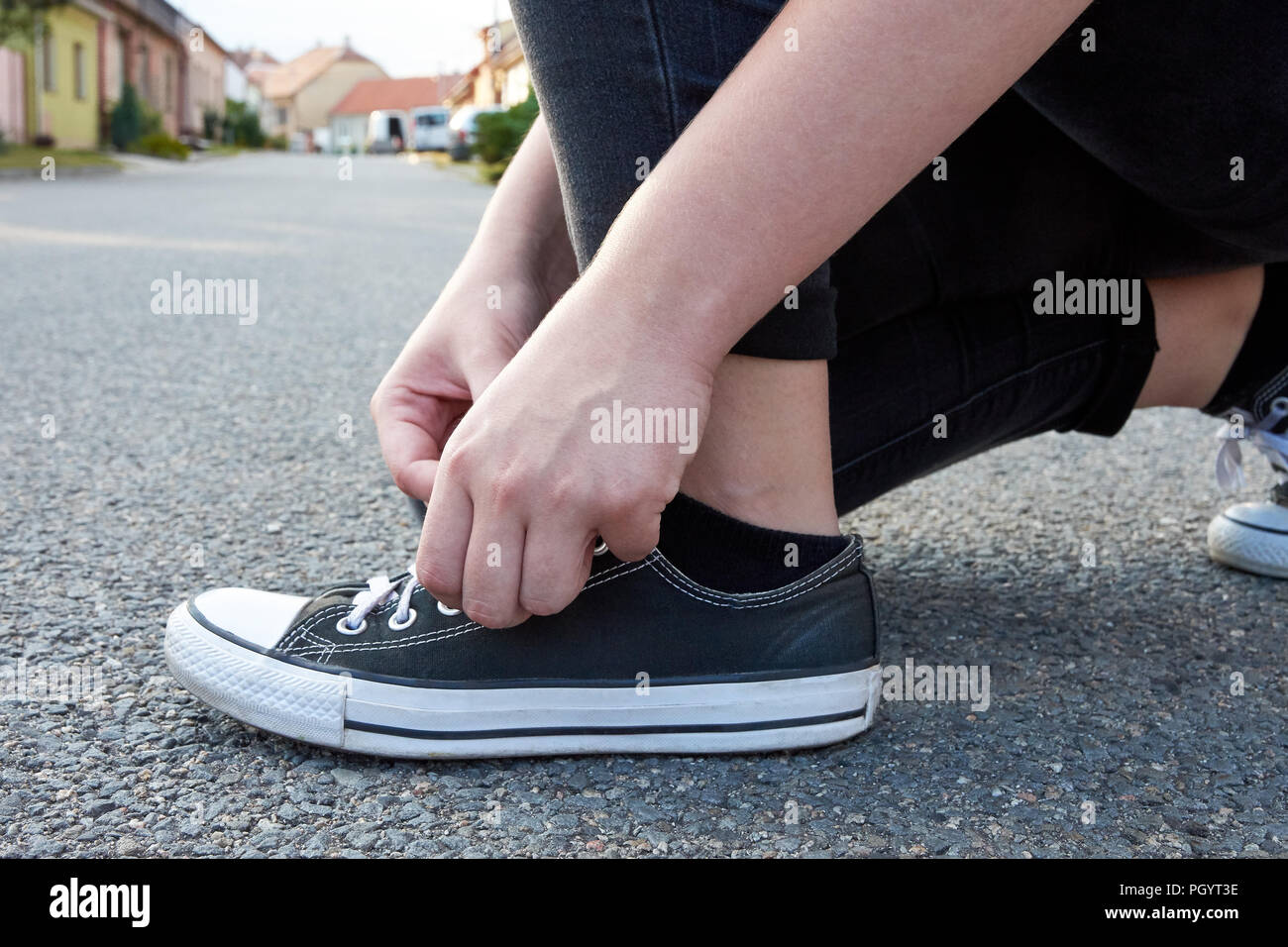Jeune femme pour attacher à lacets chaussures de sport. La route d'asphalte  sur le chemin de la ville entre les maisons Photo Stock - Alamy
