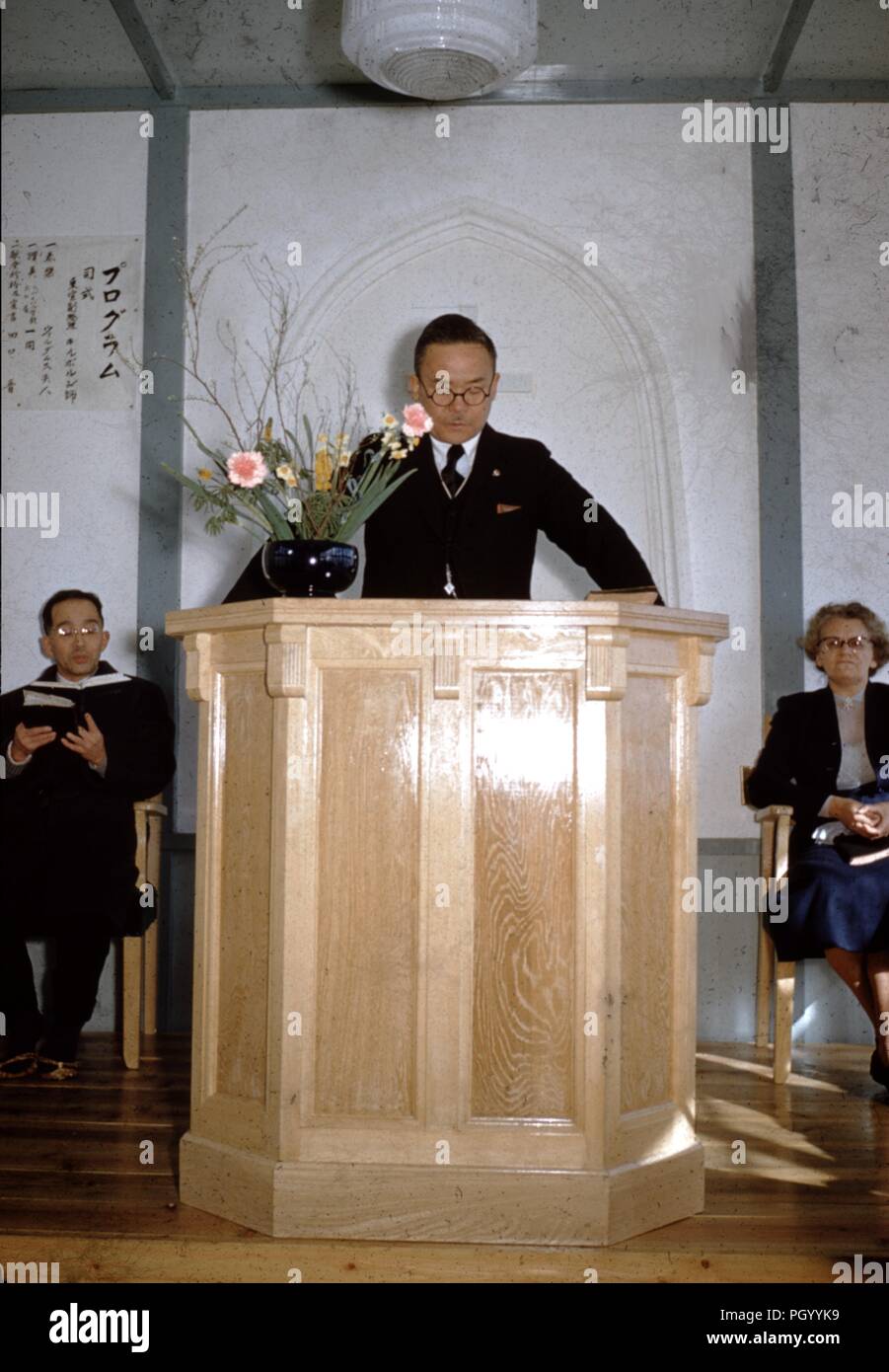 Un homme japonais se trouve à un autel et prêche à une église missionnaire chrétien, avec des femmes de race blanche assis sur le côté missionnaire, en 1955, le Japon d'après-guerre. () Banque D'Images