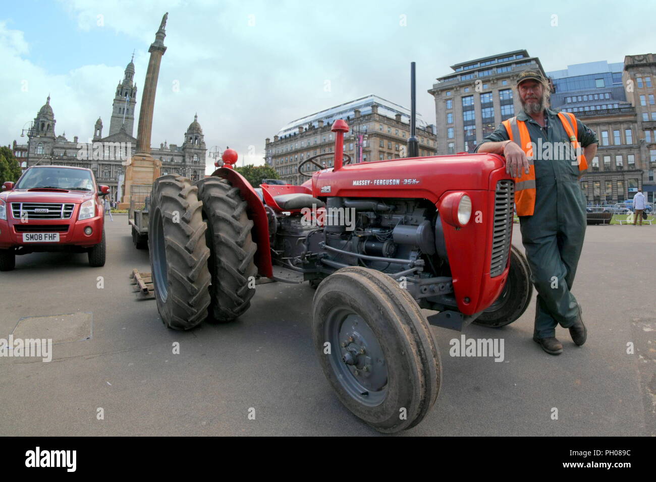 Glasgow, Ecosse, Royaume-Uni. Le 29 août, 2018. L'heure du déjeuner où les visiteurs traités pour un peu d'histoire de vie comme un rouge classique 1964 tracteur Massey Ferguson 35X apparaît dans la ville, George Square. Les habitants et les touristes regardé sur le gazon qui a été levé pour les récents Championnats Européens centre accueillant a été remplacé. Le modèle rare sport roues double pour augmenter la traction et a été modifiée par l'heureux propriétaire en photo. Gérard Ferry/Alamy news Banque D'Images