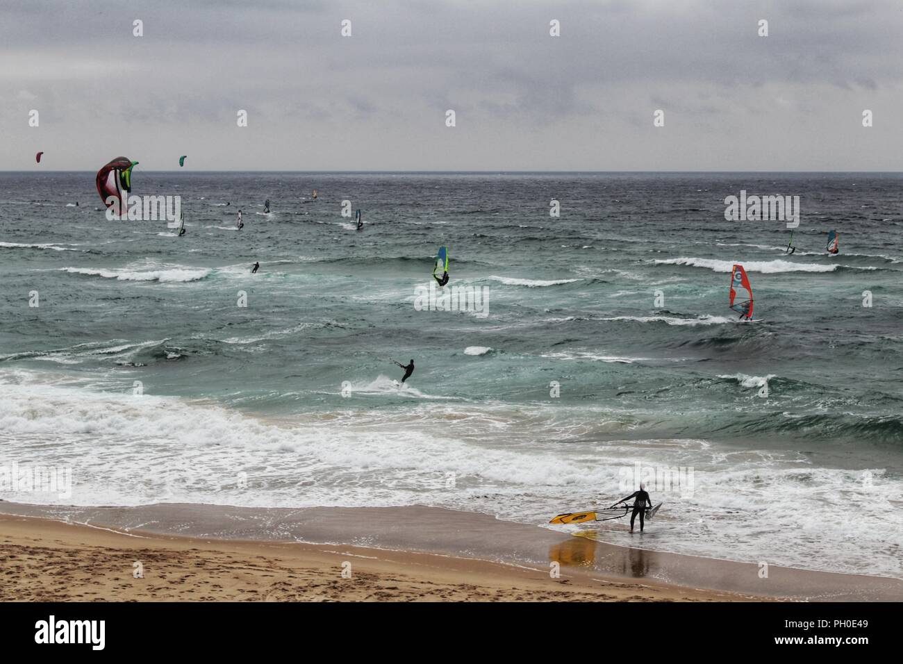 Les surfeurs à la plage de Guincho sous ciel nuageux au printemps au Portugal Banque D'Images