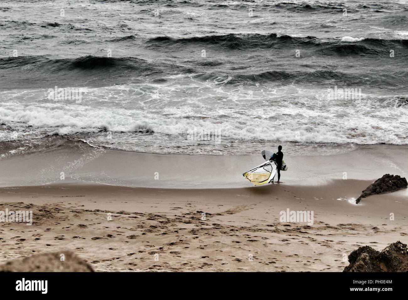 Les surfeurs à la plage de Guincho sous ciel nuageux au printemps au Portugal Banque D'Images