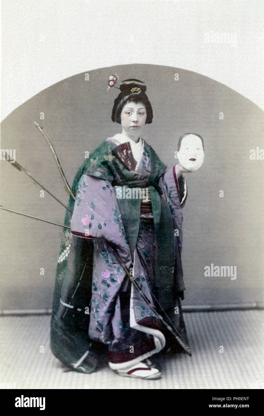 [ 1890 - Japon femme en kimono tenant un masque et des flèches ] - une femme en kimono et tradfitional hairstyle tenant un masque et d'arc et des flèches. 19e siècle vintage albumen photo. Banque D'Images