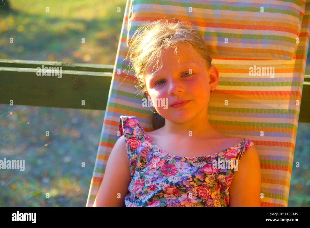 Petite fille, c'est de prendre un bain de soleil dans le jardin. Image romantique et rêveuse. L'été et l'enfance heureuse concept Banque D'Images