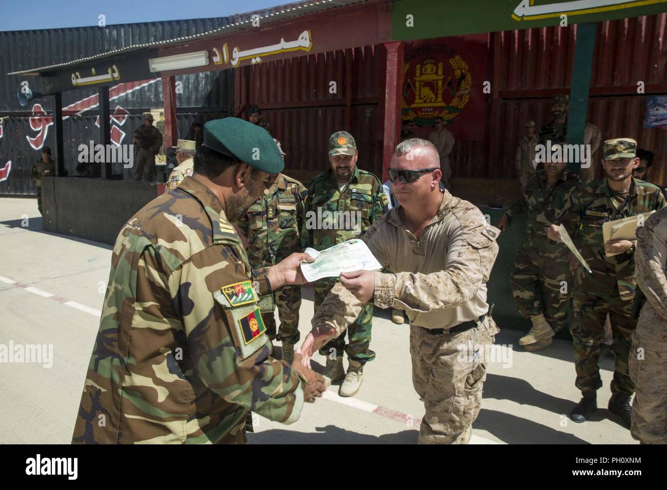 La province d'Helmand, en Afghanistan (21 juin 2018) - Un conseiller du Corps des Marines des États-Unis avec la force des mains du sud-ouest une armée nationale afghane (ANA) 215e soldat du corps de son certificat d'achèvement pendant un cours de leadership de leur diplôme au Camp Shorabak. L'ANA et 505ème de la zone de la Police nationale afghane a participé à un leadership trois semaines de cours conçu pour développer les compétences d'petit-unité. Banque D'Images