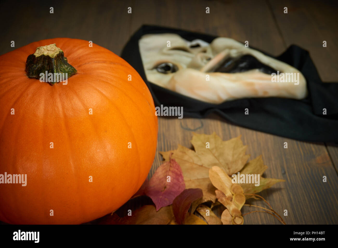 Orange citrouille les feuilles d'automne et d'halloween mask sur le vieux bois table avec copie espace libre Banque D'Images