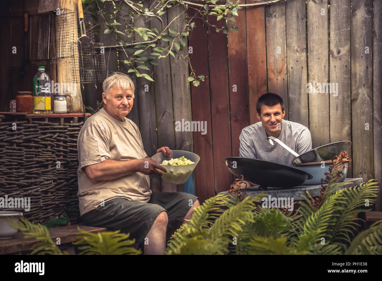 Les hommes gais à l'extérieur dans la cuisine rustique campagne vie Banque D'Images