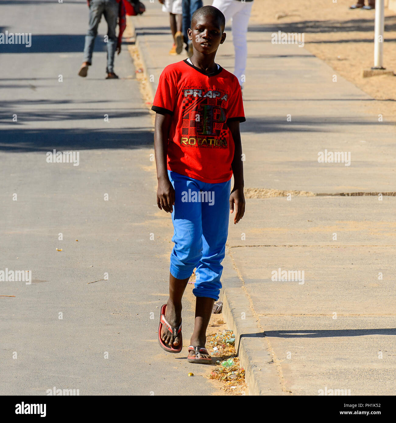 SAINT LOUIS, SÉNÉGAL - Apr 24, 2017 : garçon sénégalais non identifiés en  chemise rouge et pantalon bleu marche à côté de la route de Saint Louis,  l'un des plus grands Photo Stock - Alamy