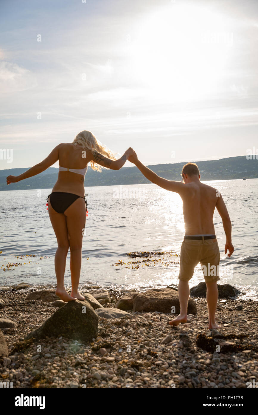 Dans l'amour couple holding hands at the beach contre sun Banque D'Images