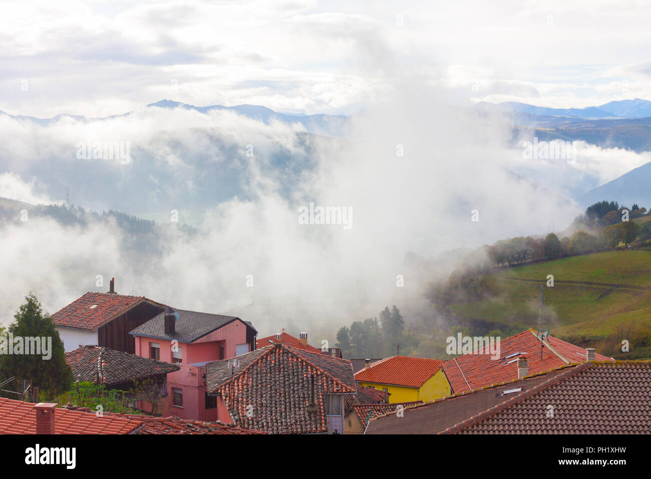 Maisons avec des montagnes dans le brouillard à l'arrière-plan à Tineo, Asturias, Espagne Banque D'Images