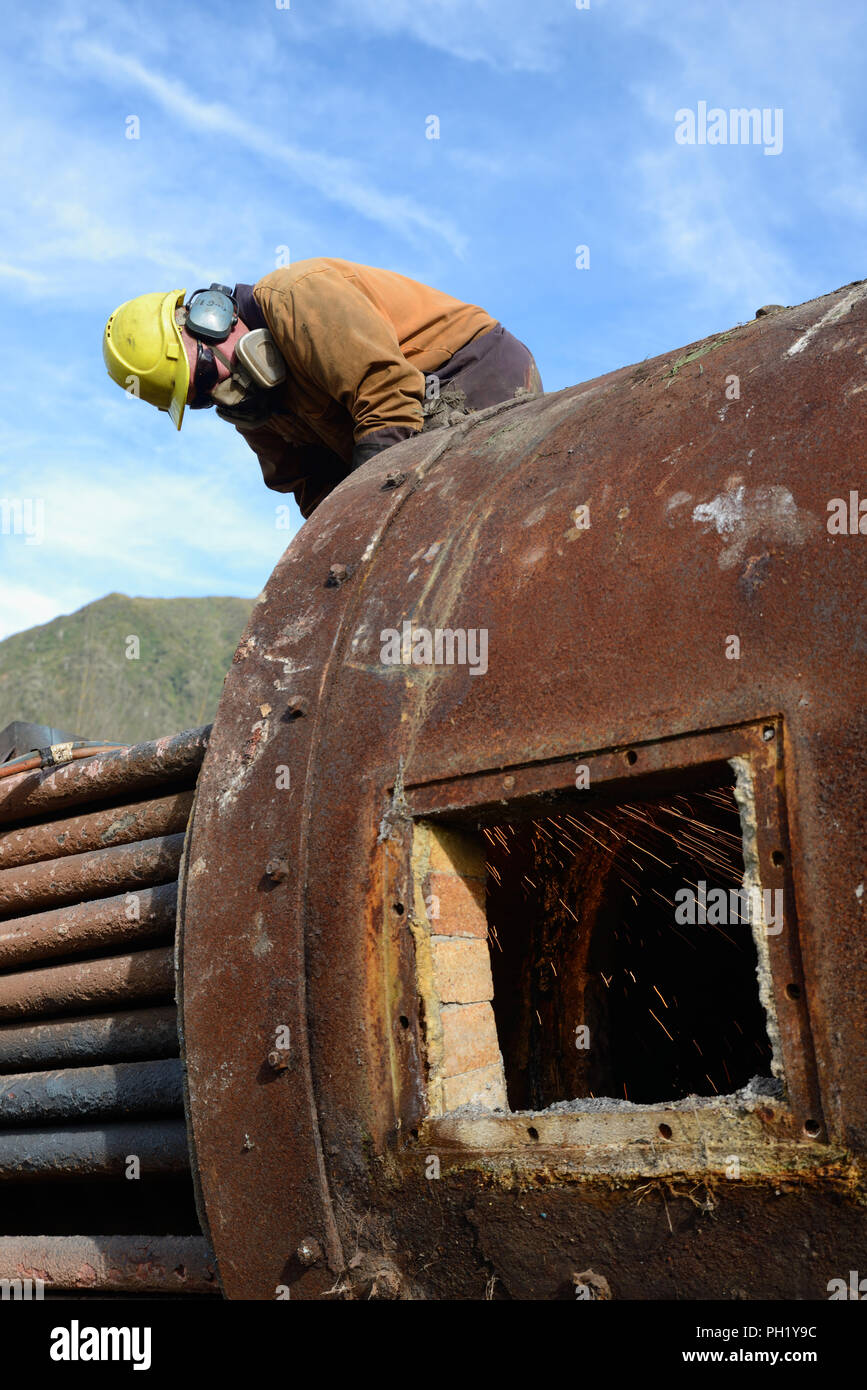 Greymouth, Nouvelle-Zélande, le 14 mai 2018 : Un ingénieur de coupe une ancienne chaudière pour la ferraille Banque D'Images