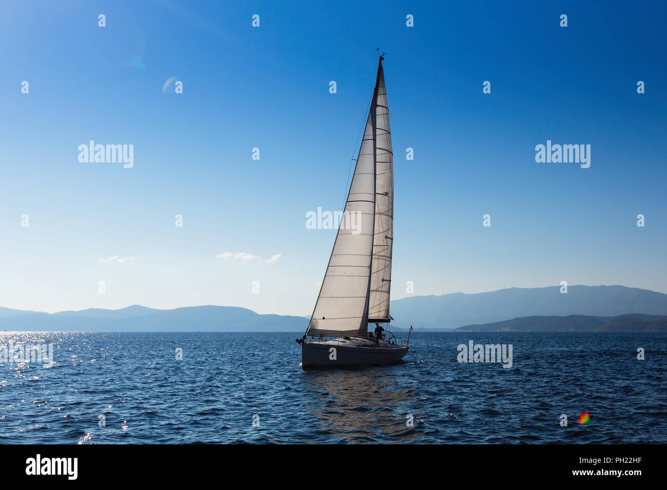 Yacht à voile avec voiles blanches dans la mer près de la côte de la Grèce. Banque D'Images
