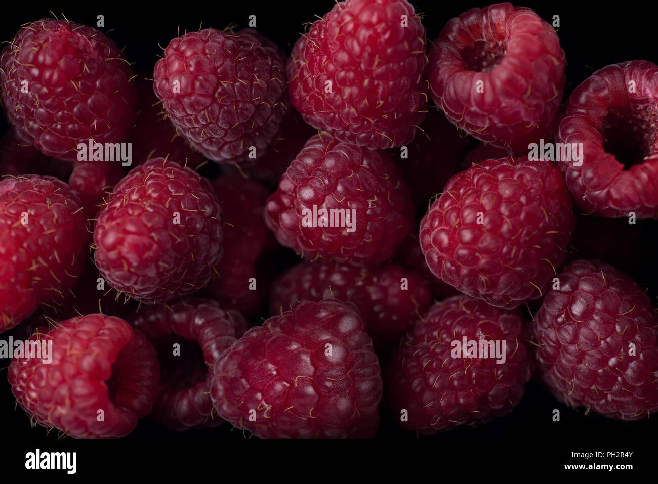 La diffusion de petits fruits framboise sur fond noir Banque D'Images
